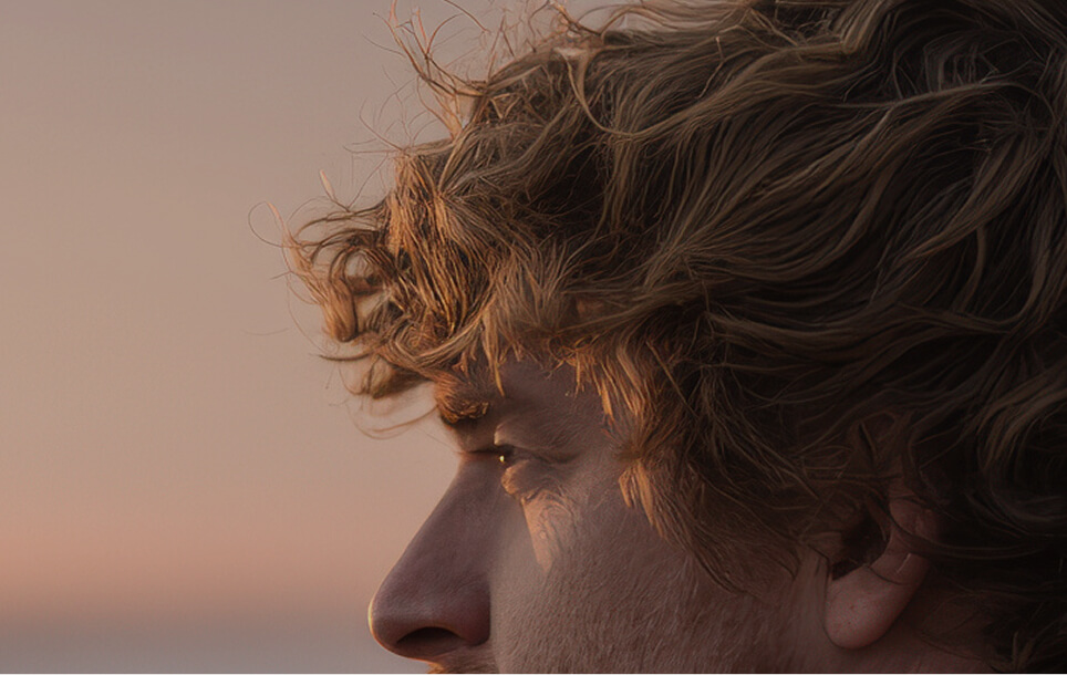 Primo piano di profilo di un giovane uomo illuminato dalla luce del tramonto, immagine evocativa di vitalità, energia e fiducia in sé stessi